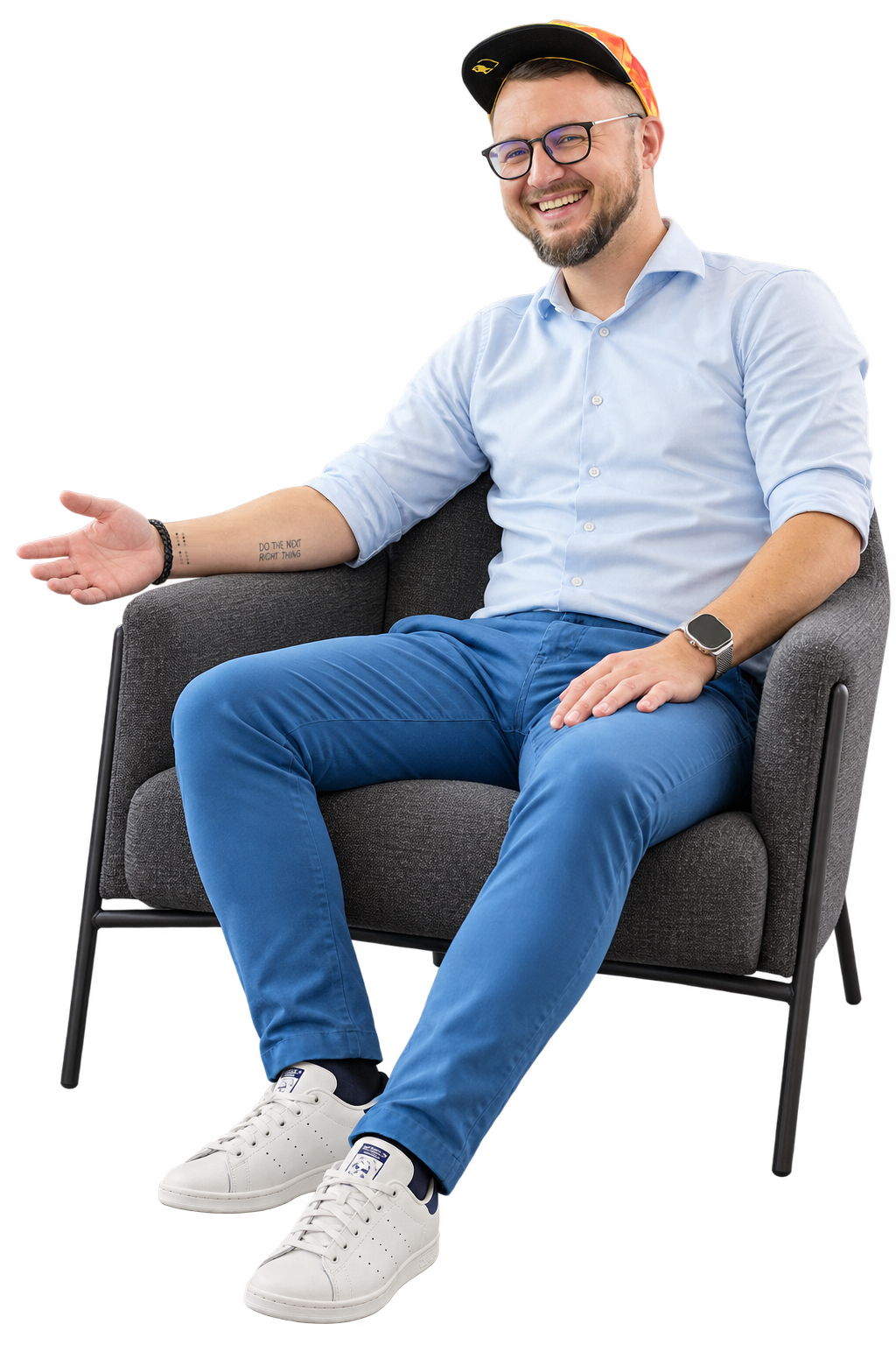 Kamil Zych seated in an armchair, wearing a blue shirt, cap and white trainers, with a visible tattoo on his right forearm